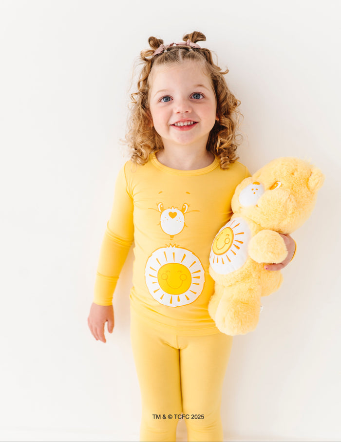 Child wearing Care Bears Funshine Bear yellow bamboo pajamas with sun belly badge