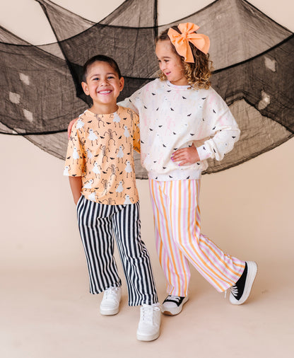 Two children standing in front of a black net against a beige background