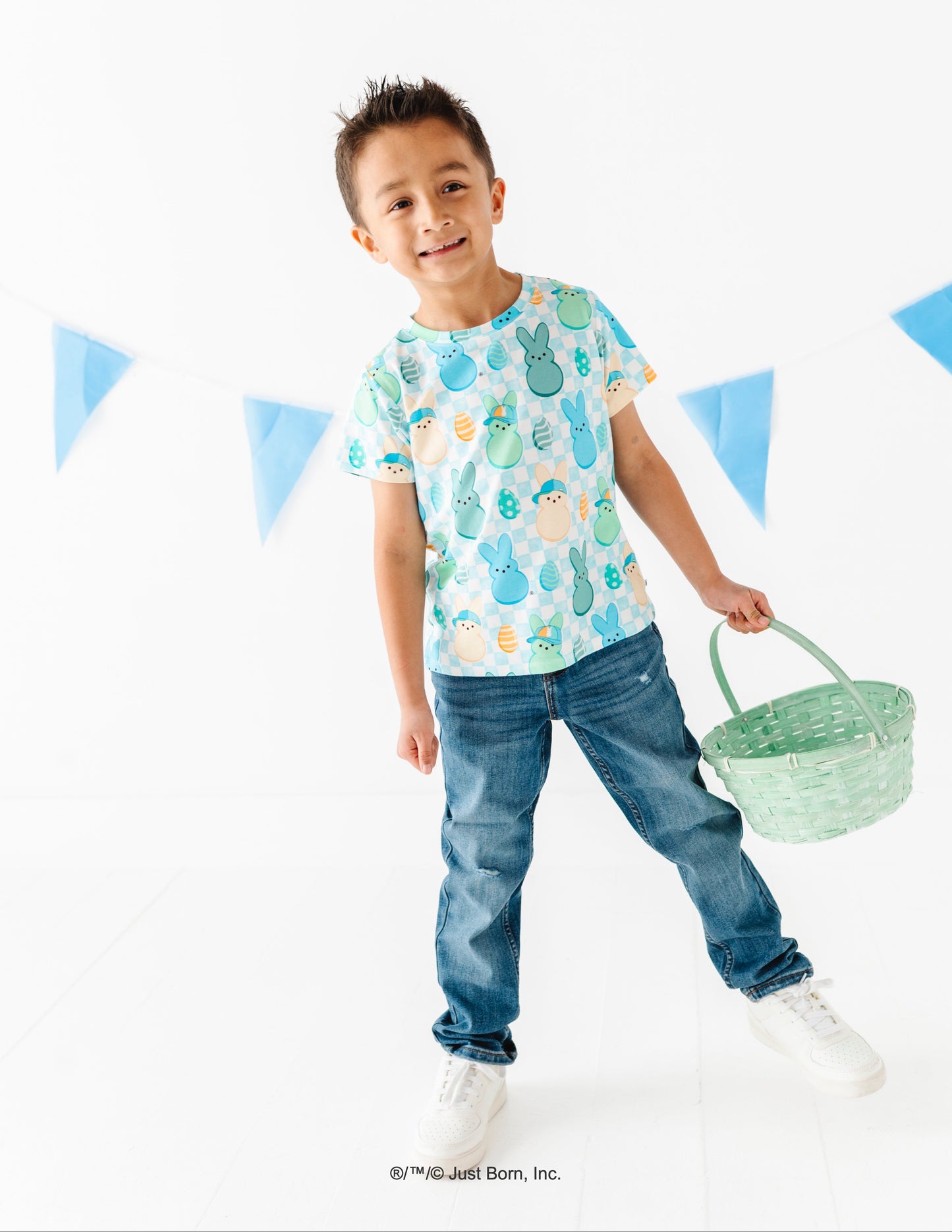 Child wearing a patterned PEEPS® shirt and jeans, holding a basket against a white background with blue triangle flags.