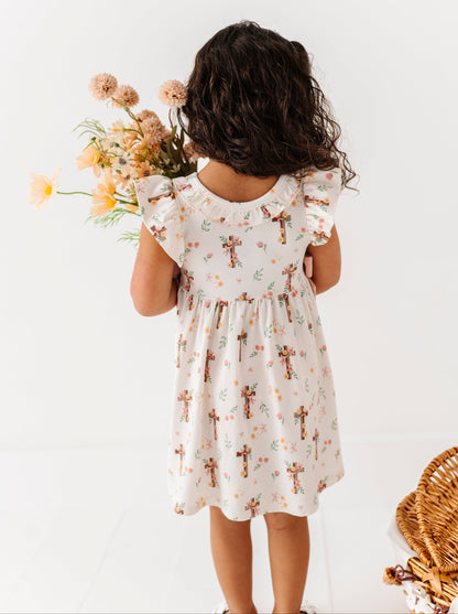 Child wearing a floral dress holding flowers against a white background