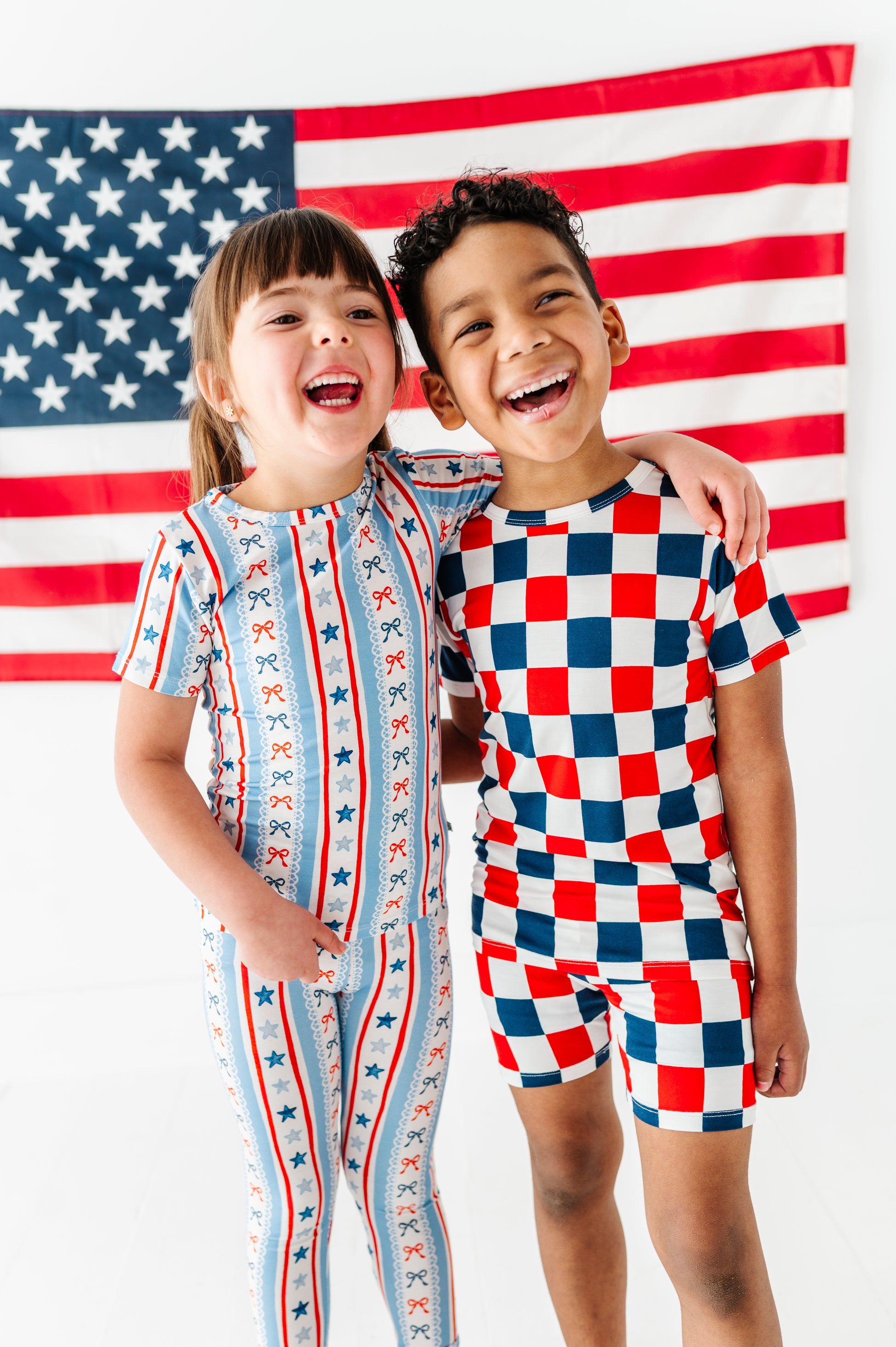 Brother and sister wearing coordinating bamboo pajama outfits in patriotic prints 