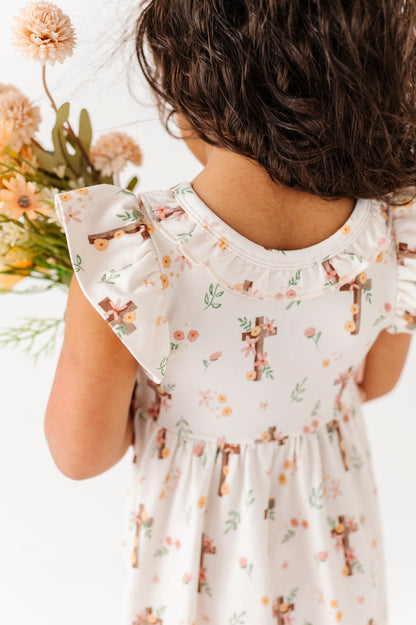 Child wearing a floral Easter dress holding flowers, with a focus on the dress and child's back.