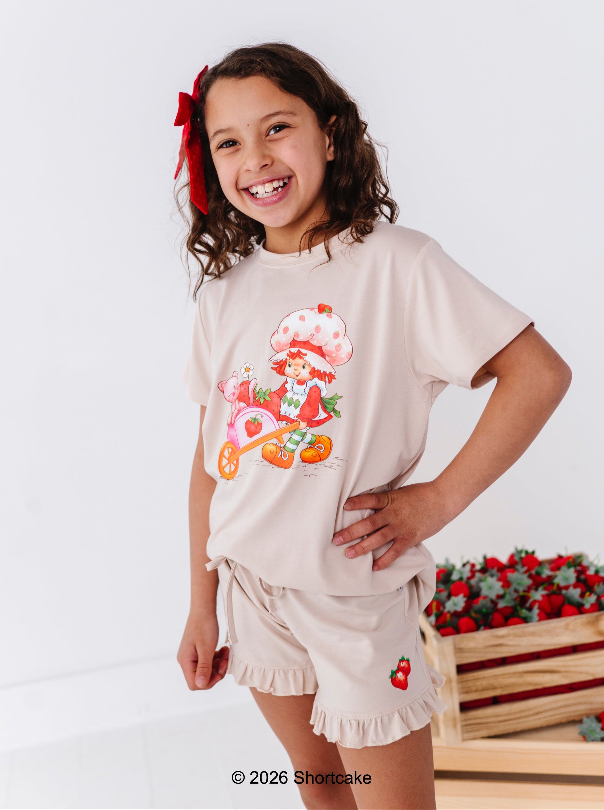 Young girl wearing a cream-colored Strawberry Shortcake™ outfit, standing against a white background.