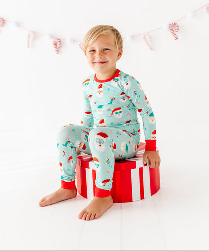 Child wearing festive bamboo pajamas sitting on a gift box with a white background