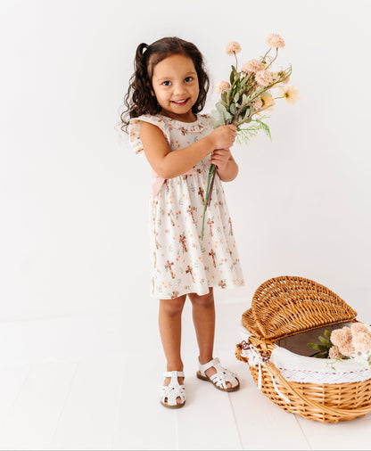 Young girl holding flowers next to a wicker basket on a white background