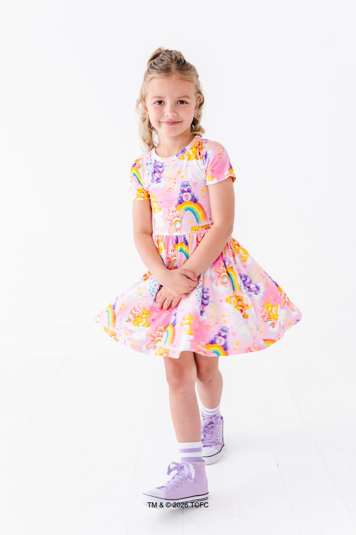 Young girl wearing a colorful Care Bears™ bamboo dress on a white background