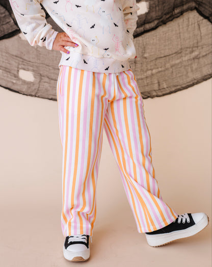 Child wearing a patterned sweatshirt and striped pants on a beige background