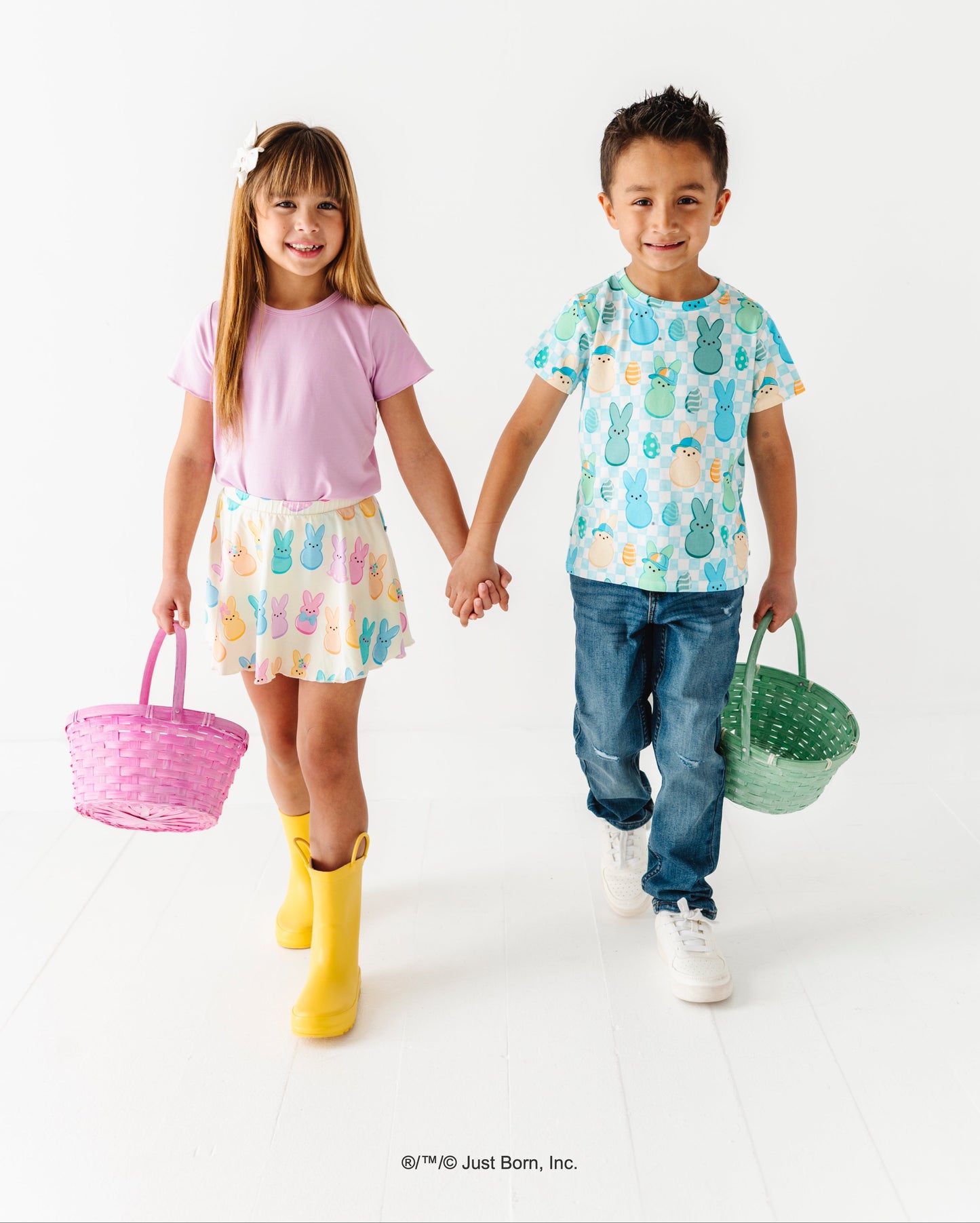 Two children holding hands, one with a pink basket and the other with a green basket, on a white background.