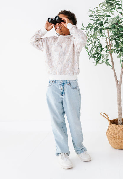 Person holding binoculars in a minimalistic setting with a plant and basket.