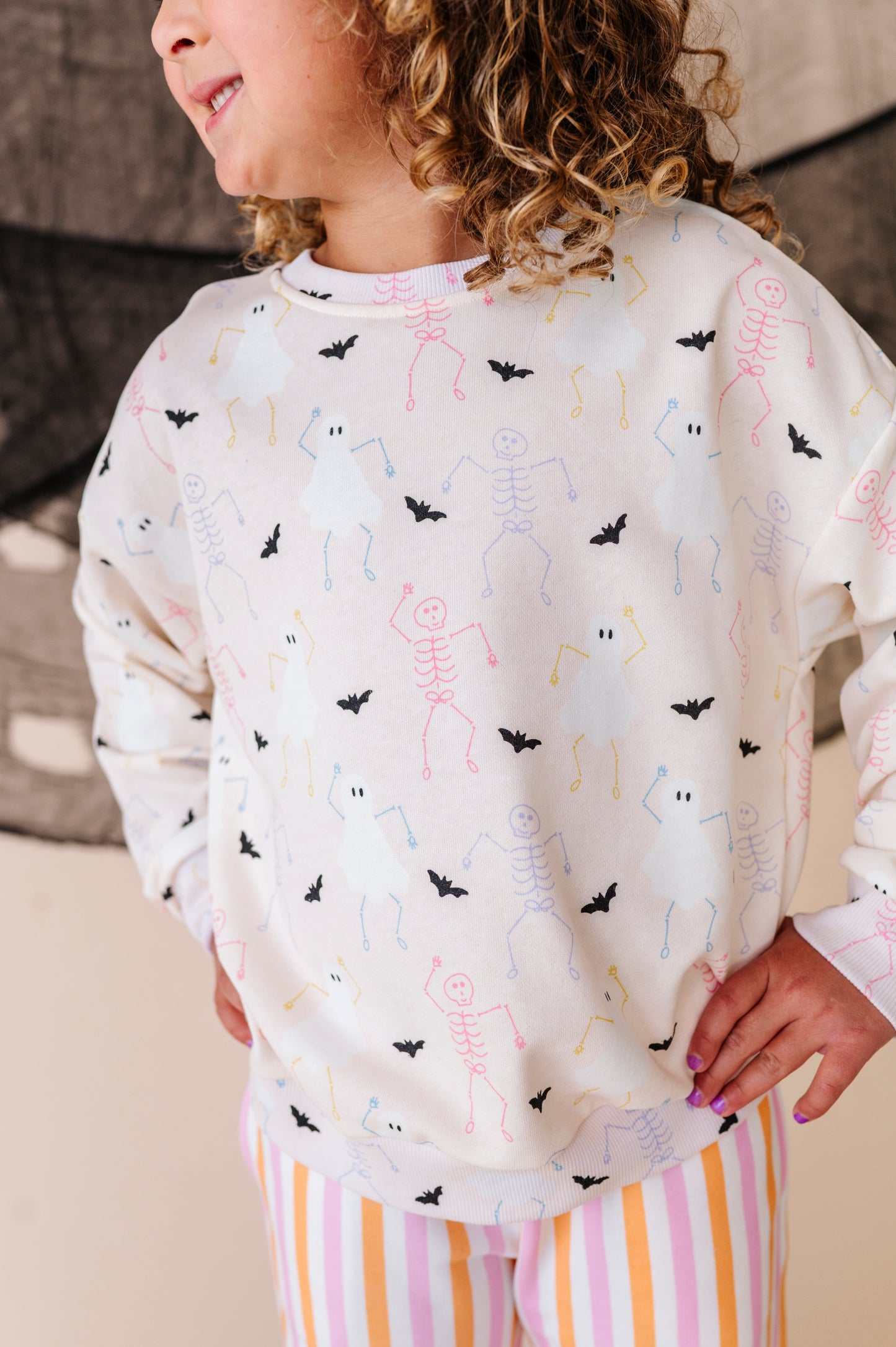 Child wearing a sweatshirt set with skeleton, ghost,  and bat pattern
