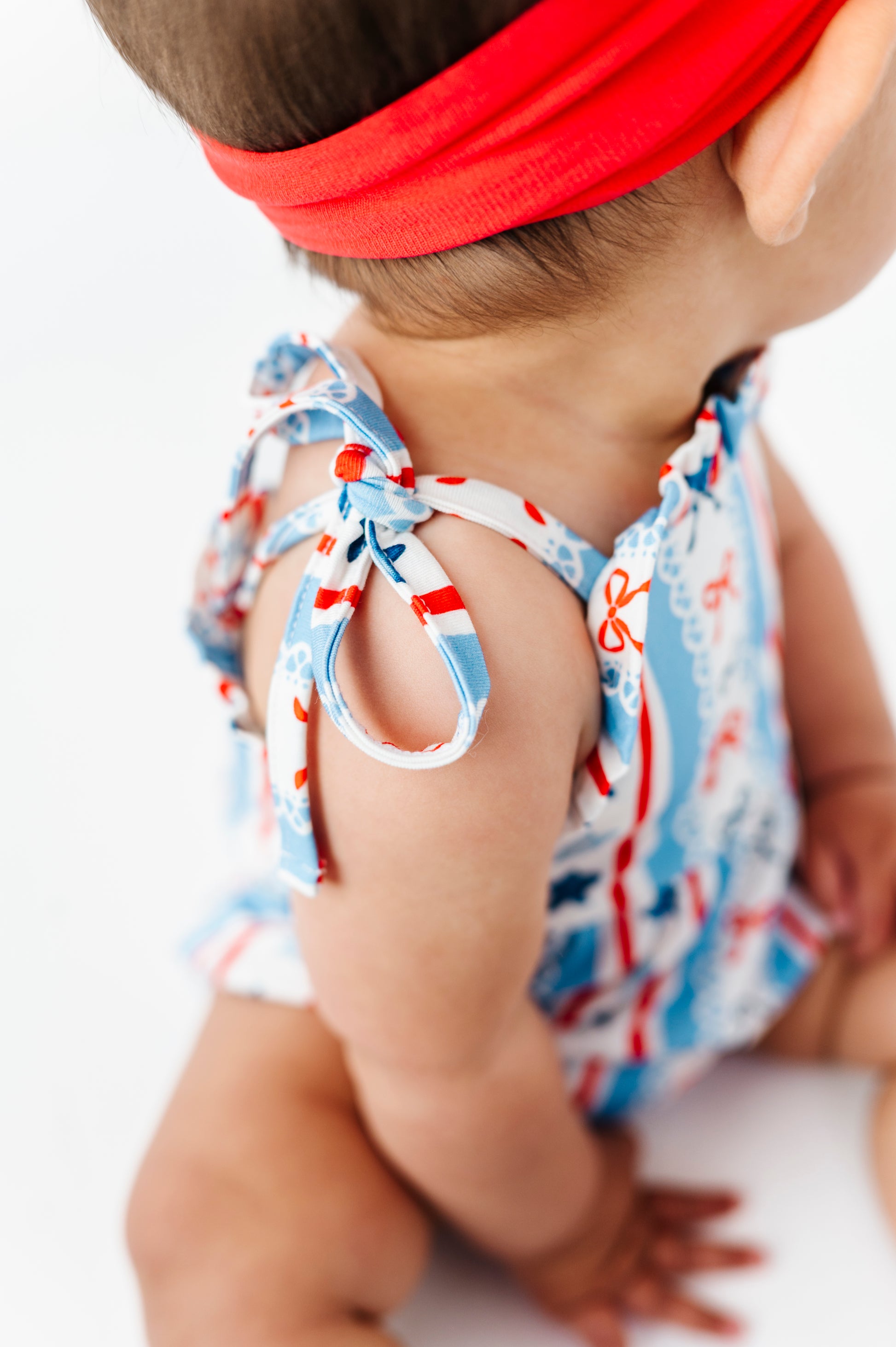 Baby girl wearing a patriotic bamboo bubble romper with red, white, and blue accents on a white background