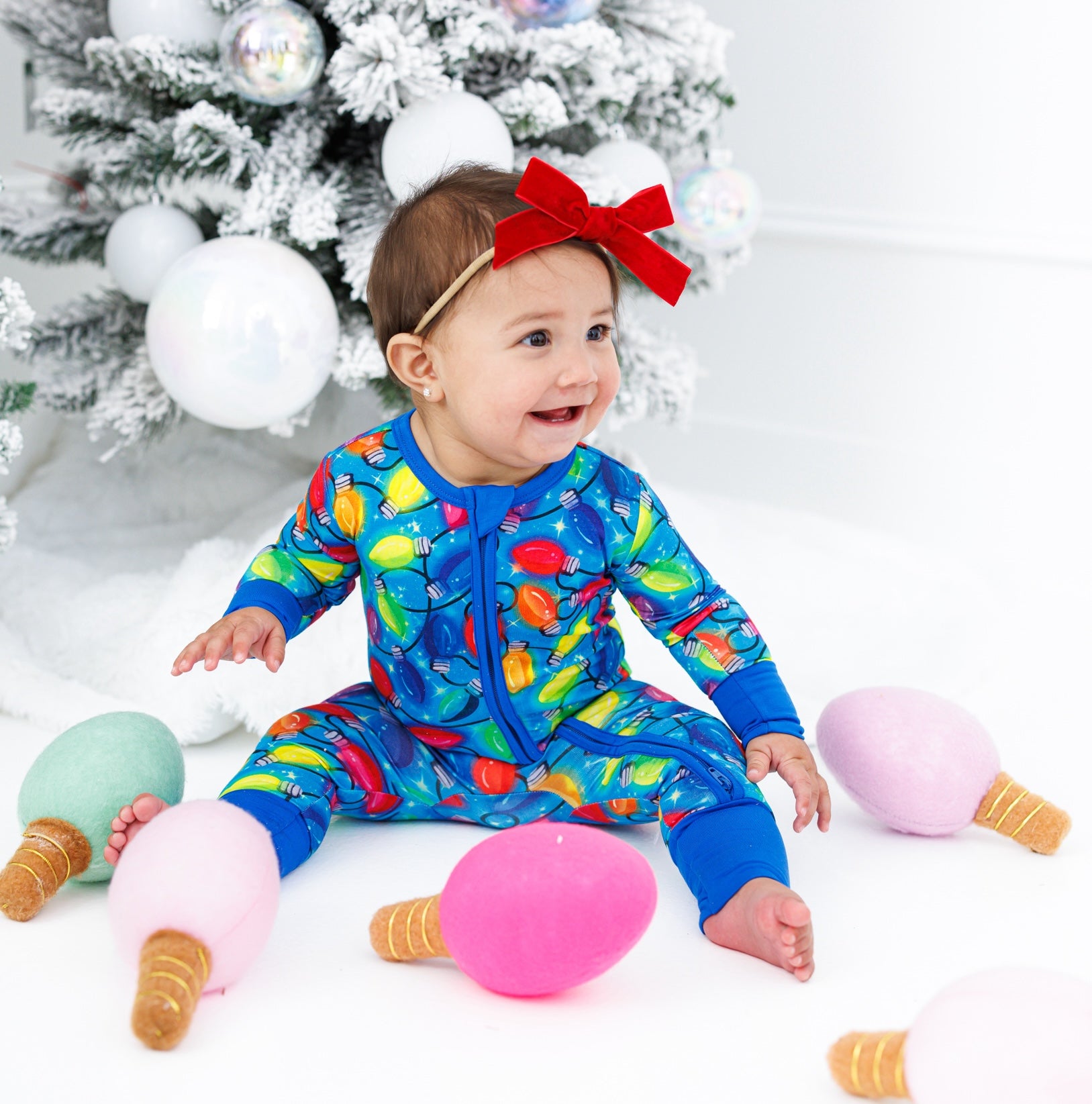 Little girl wearing a zip romper with a headband with red velvet bow