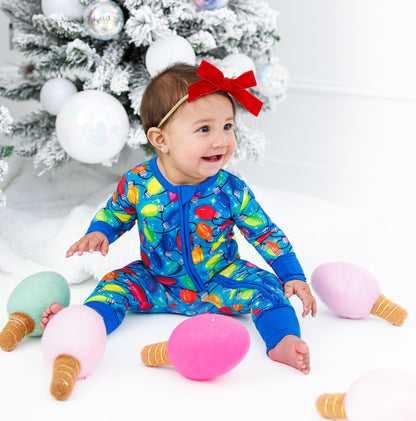Little girl wearing a zip romper with a headband with red velvet bow
