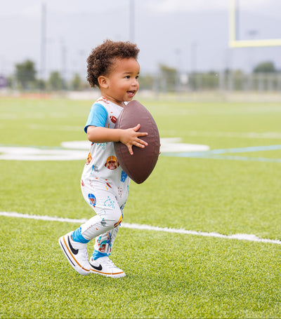 Child holding a football on a sports field