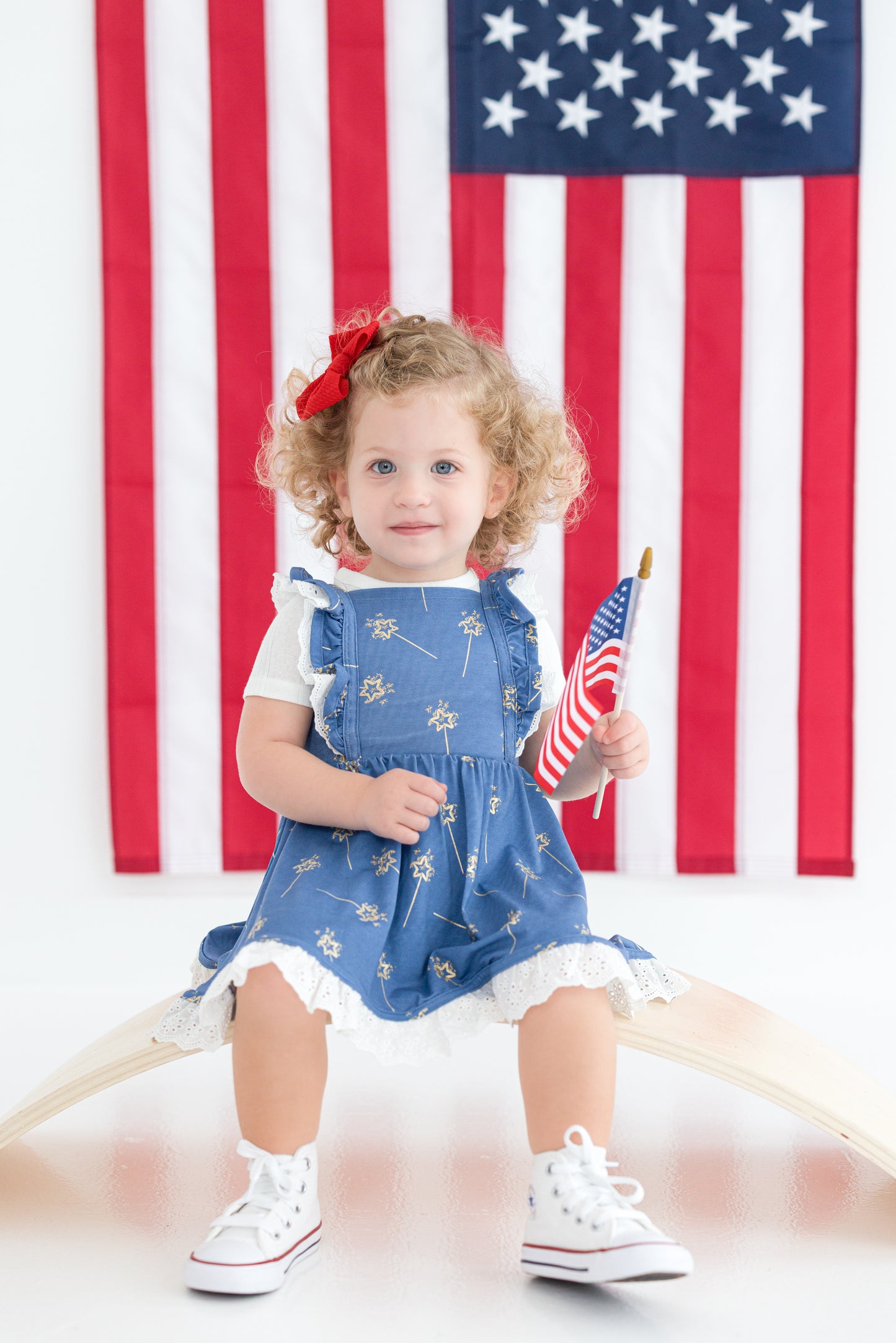 Toddler girl in blue patriotic twirl dress with ruffle straps and eyelet hem
