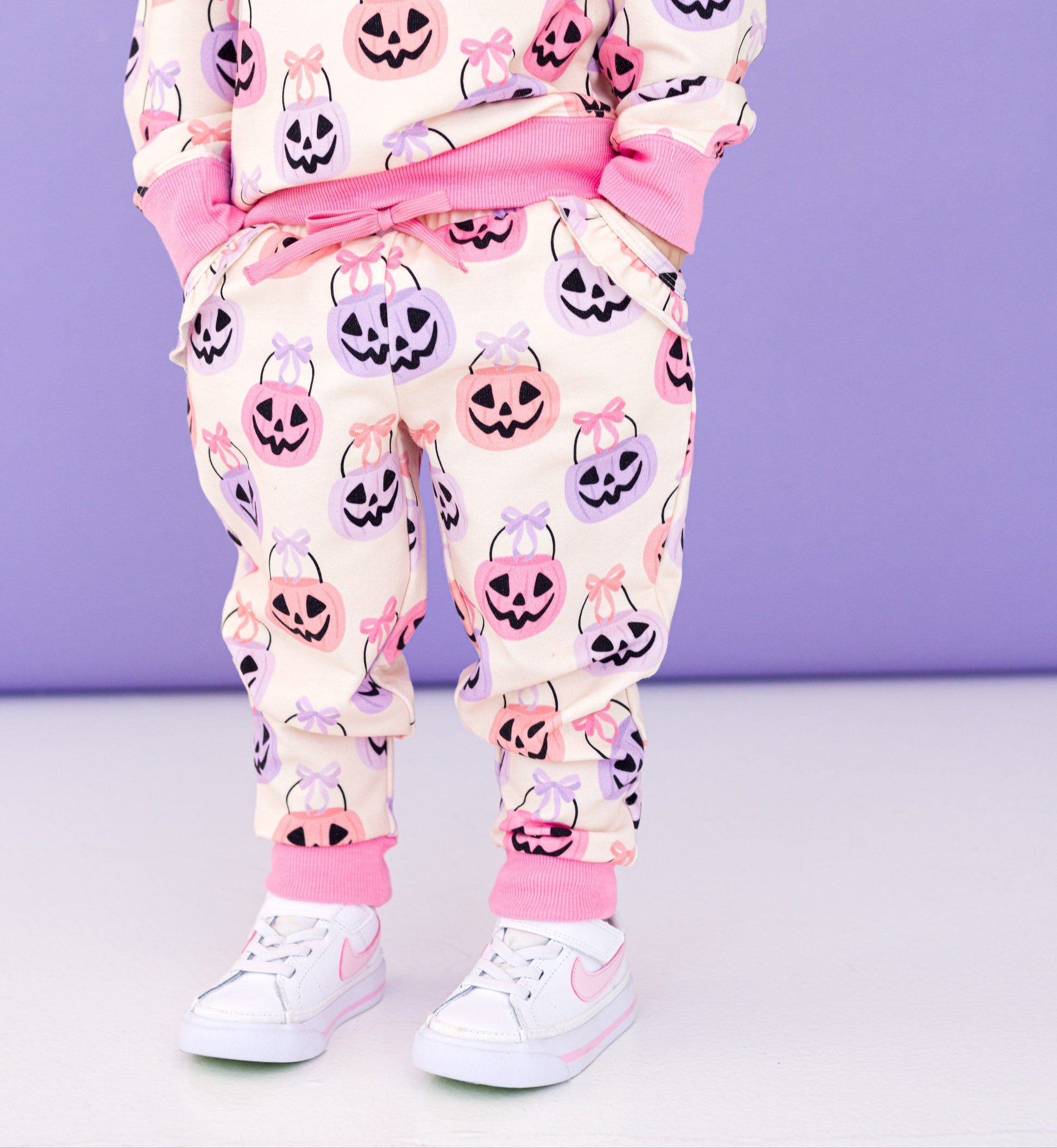 Child wearing a bamboo Halloween-themed jogger set with pumpkins and ghosts on a purple background