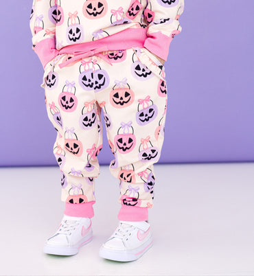 Child wearing a bamboo Halloween-themed jogger set with pumpkins and ghosts on a purple background
