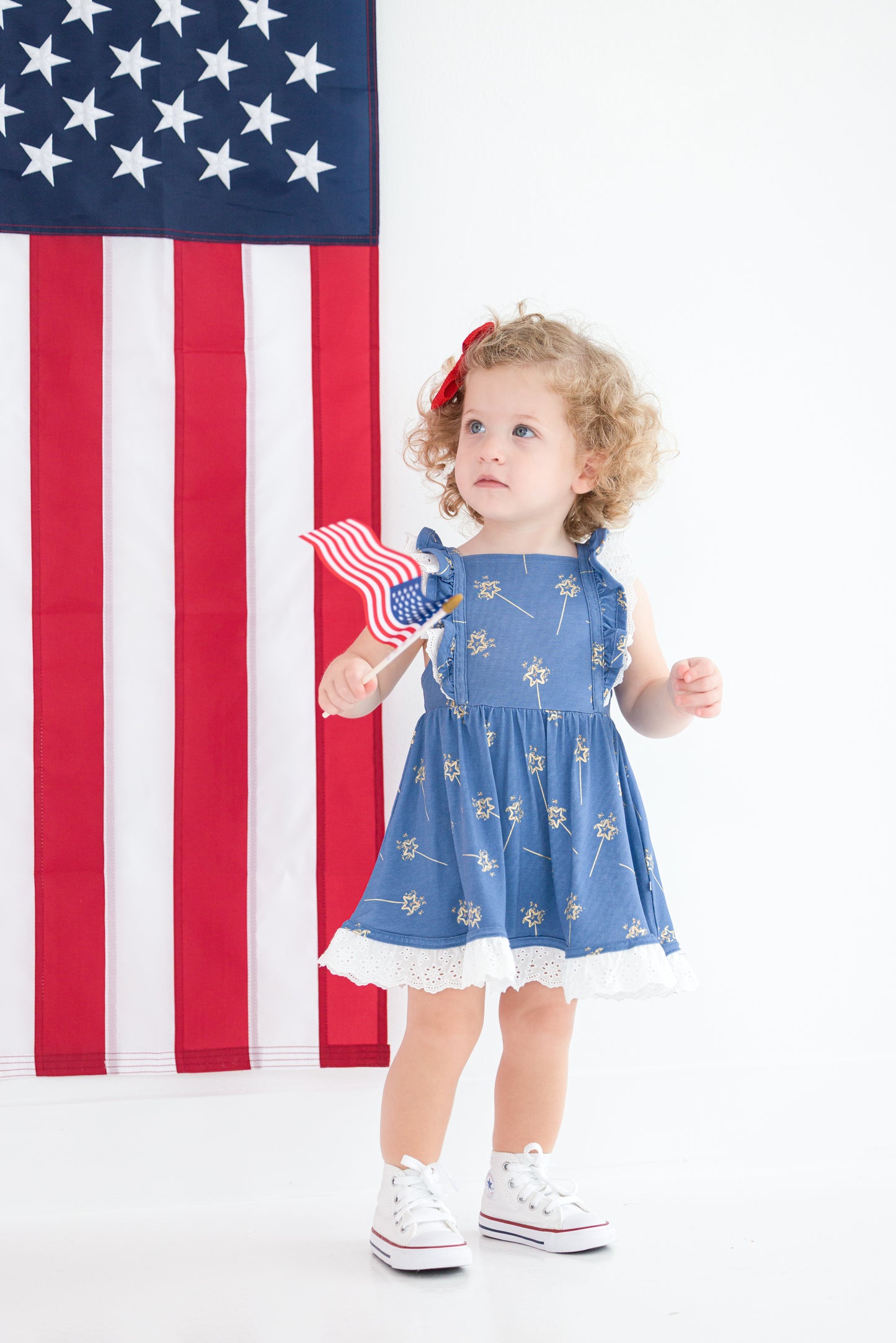 Toddler girl in blue patriotic twirl dress with ruffle straps and eyelet hem