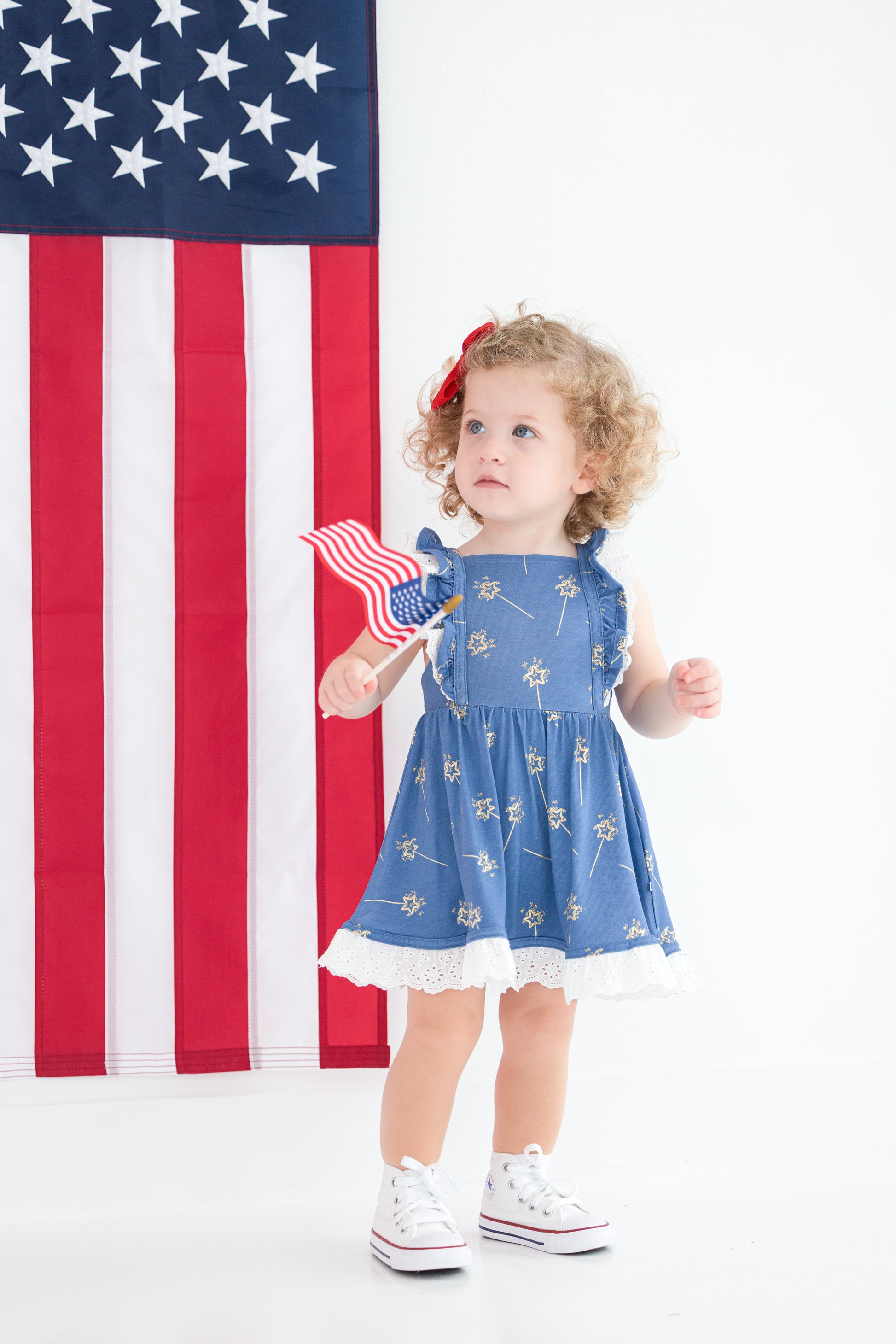 Toddler girl in blue patriotic twirl dress with ruffle straps and eyelet hem