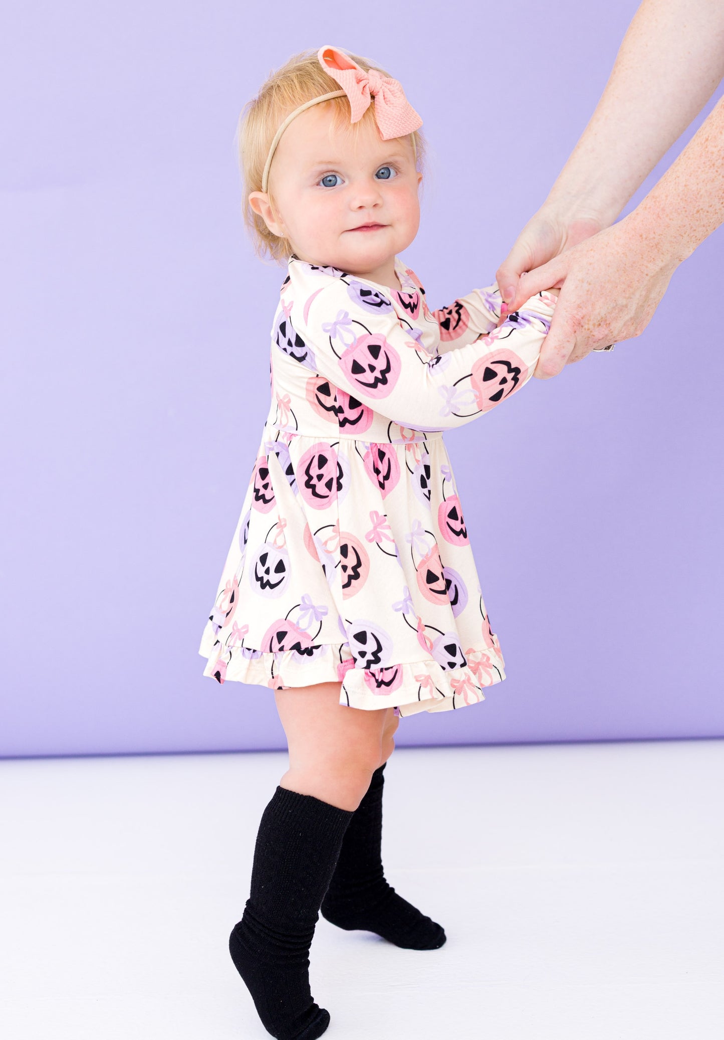 Child wearing a bamboo dress with Halloween design against a light purple background