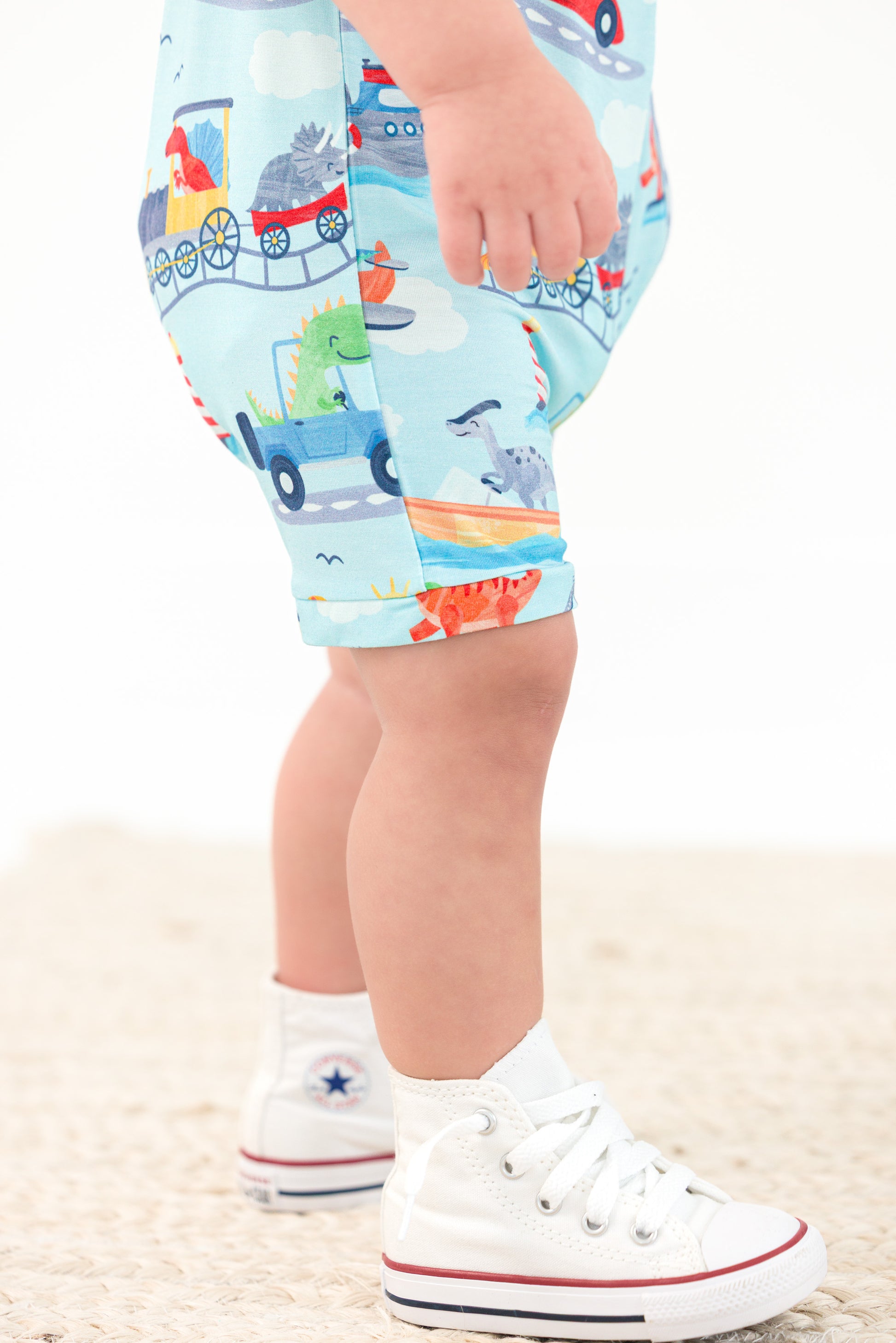 Child wearing colorful bamboo short zip romper with an animal and transportation print on a white background