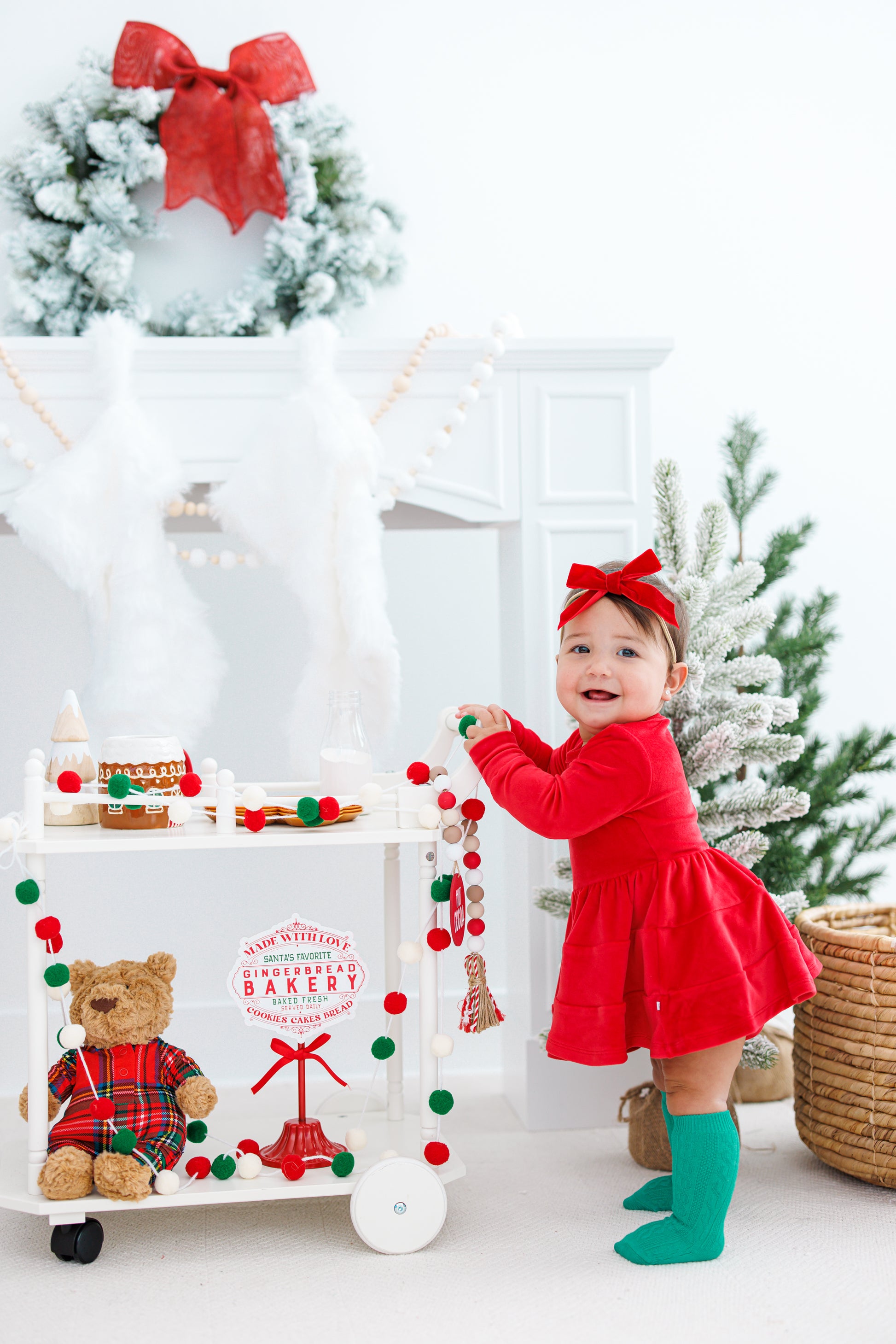 Baby at a Christmas scene wearing a red velvet dress