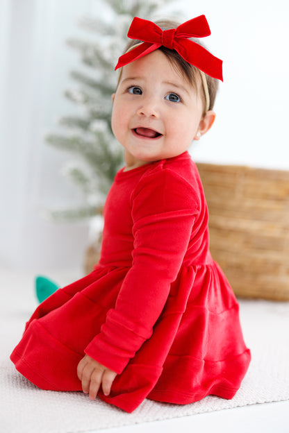 Little girl in a velvet red dress with a red velvet bow