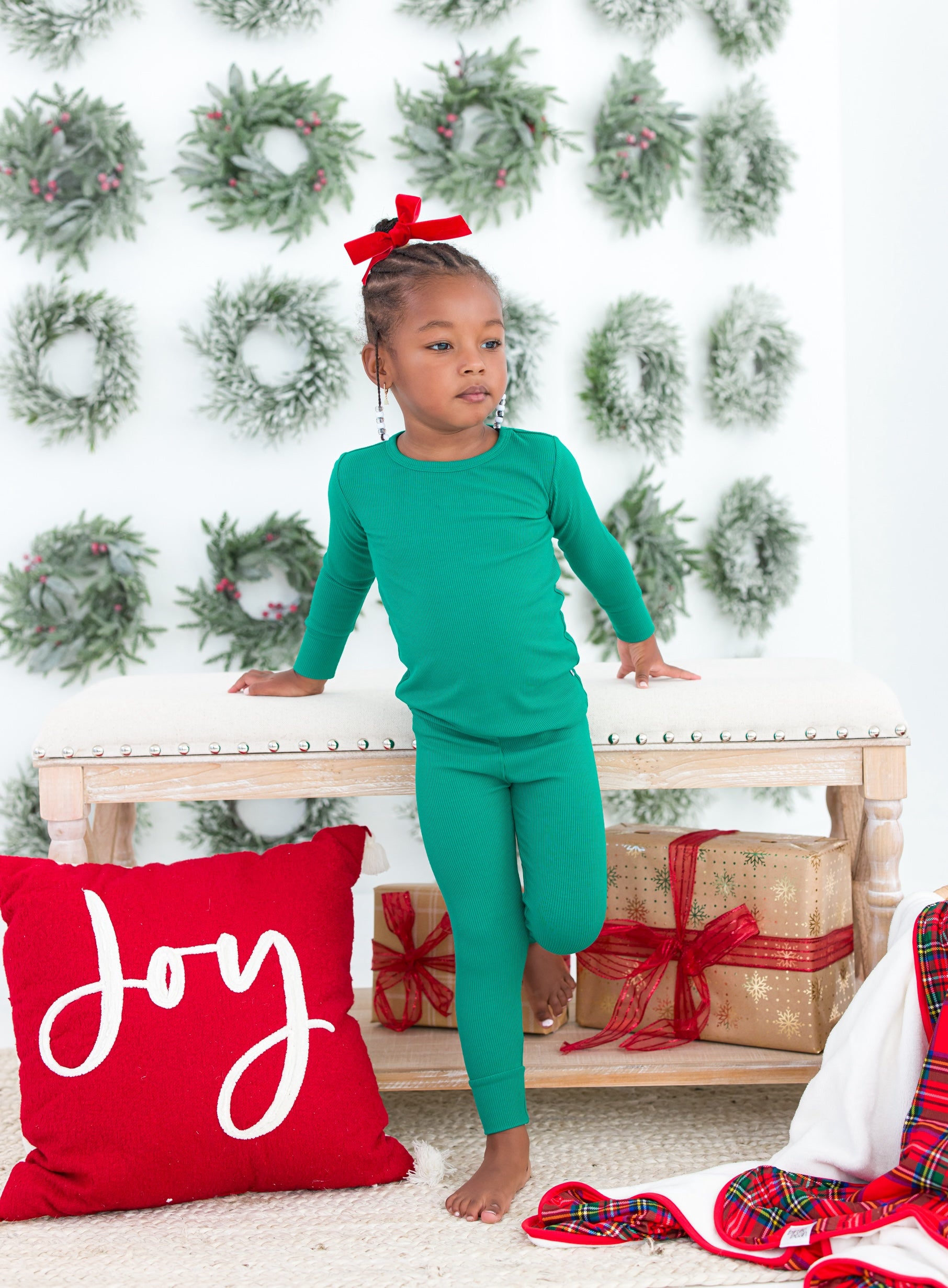 Little girl wearing green pajama set with red bow