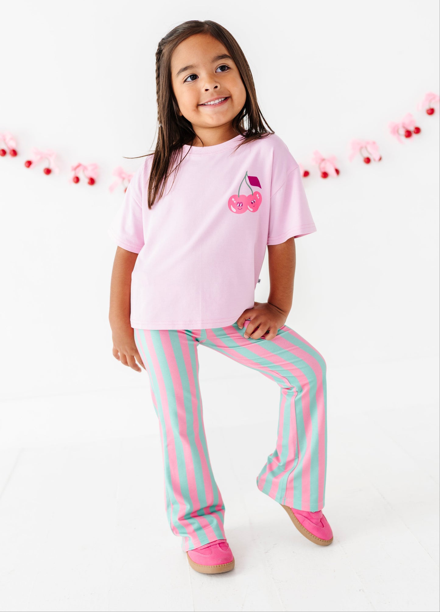 Young girl wearing striped green and pink pants with a pink tee shirt.