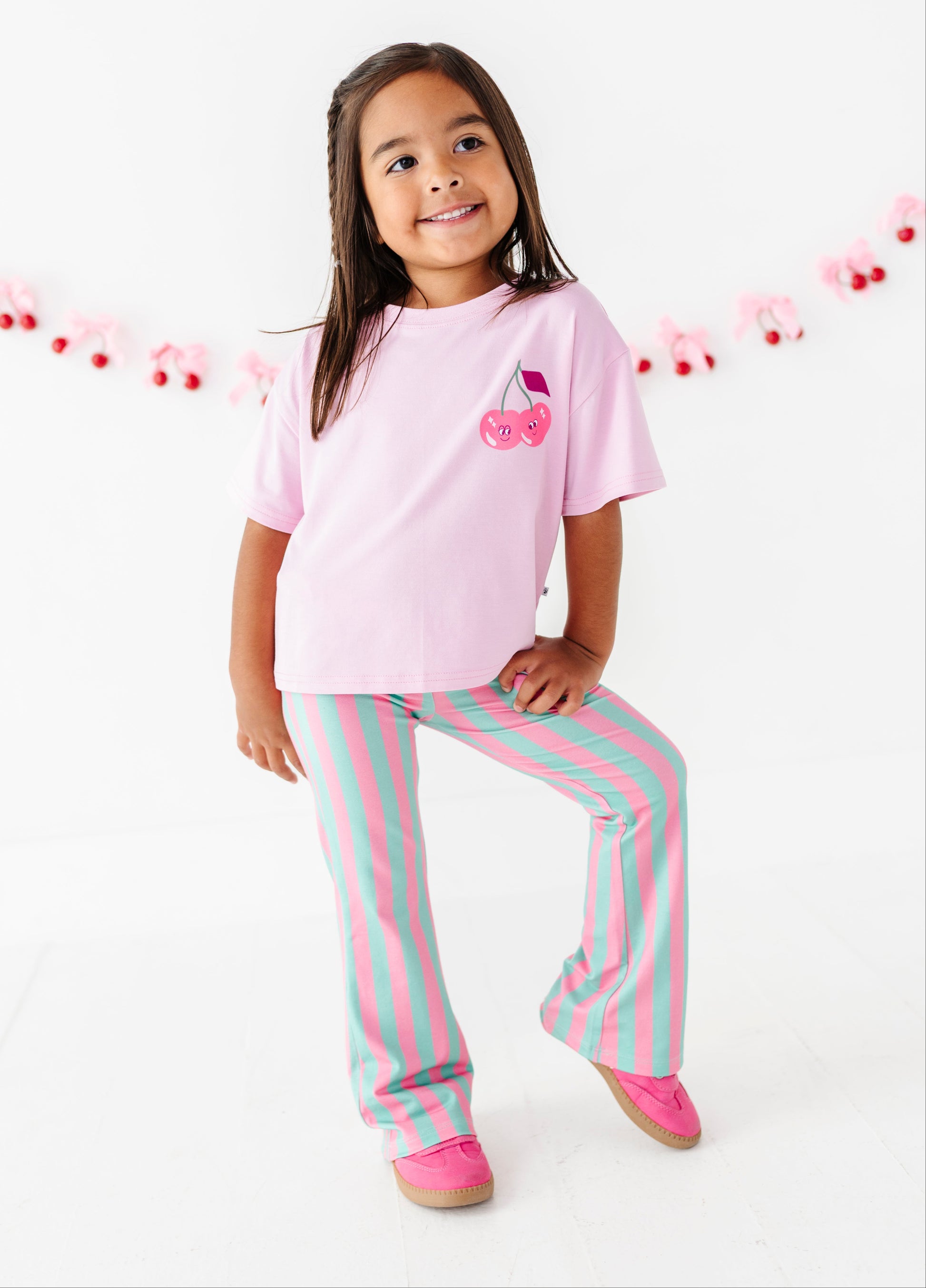 Young girl wearing striped green and pink pants with a pink tee shirt.