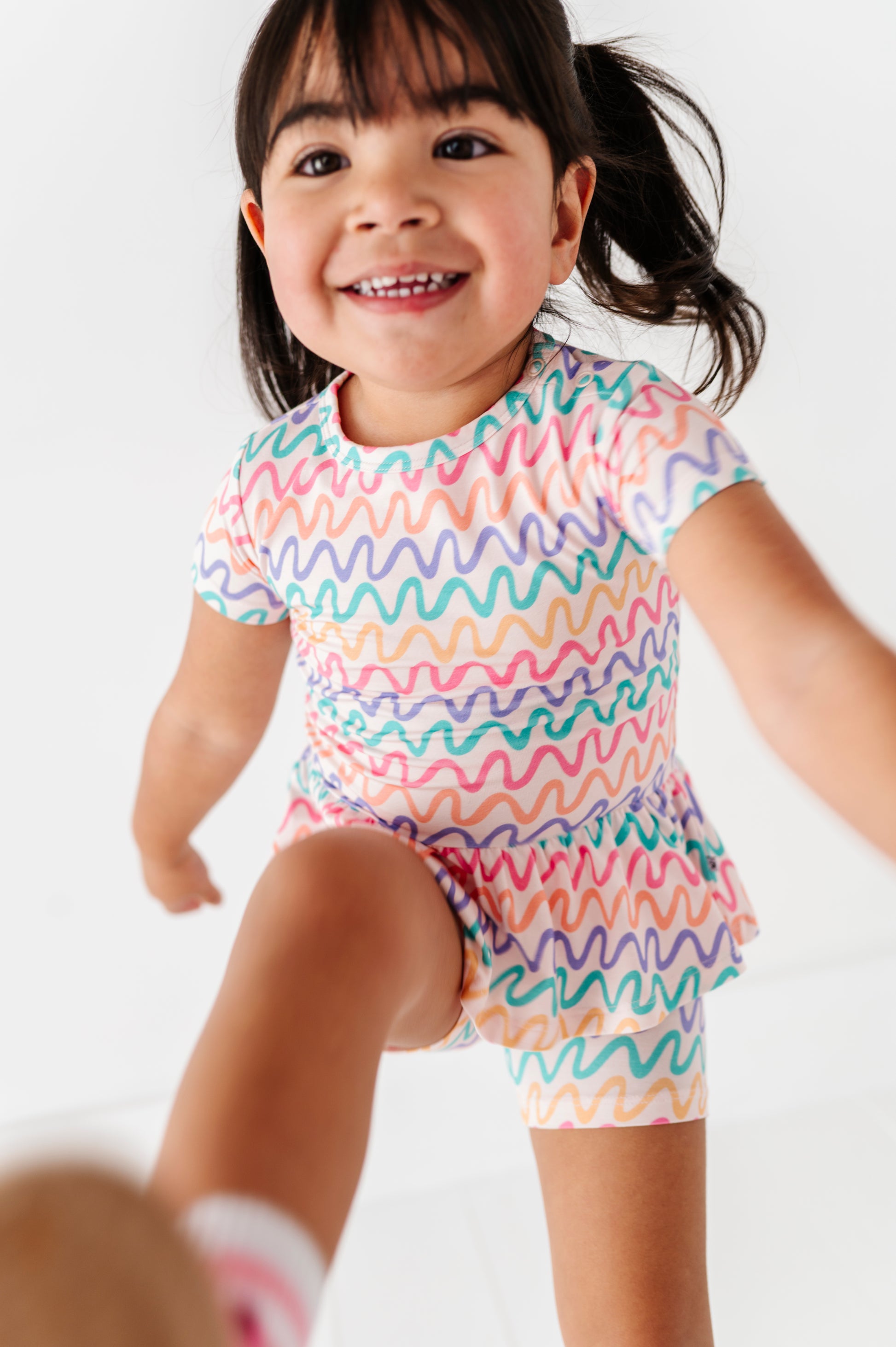 Child wearing a colorful wavy patterned bamboo outfit on a white background