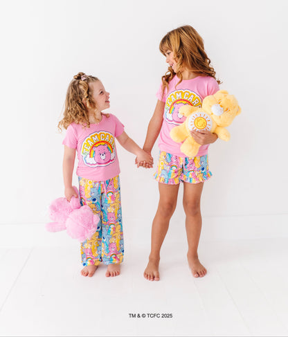 Two children wearing matching Care Bears™ Stare pajama sets holding hands and smiling