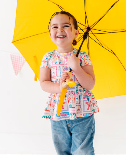Child holding a yellow umbrella against a white background