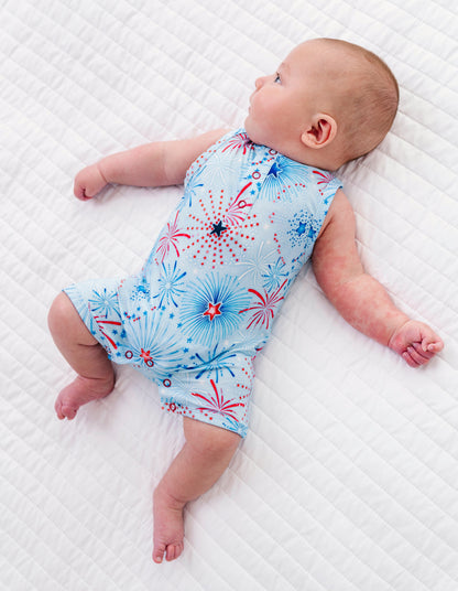 Baby lying on a white textured surface wearing a blue bamboo 4th of July romper.
