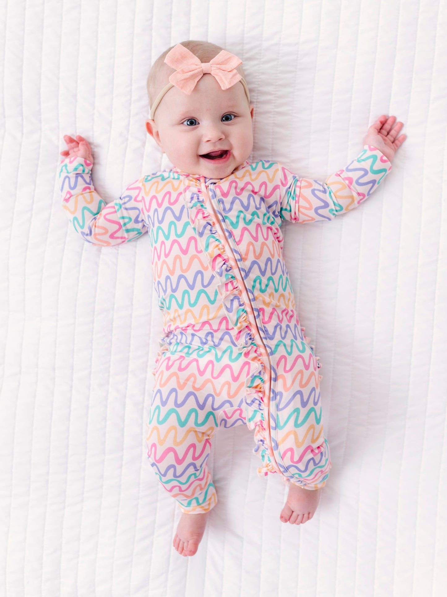 Baby wearing a colorful wavy patterned bamboo convertible romper on a white background