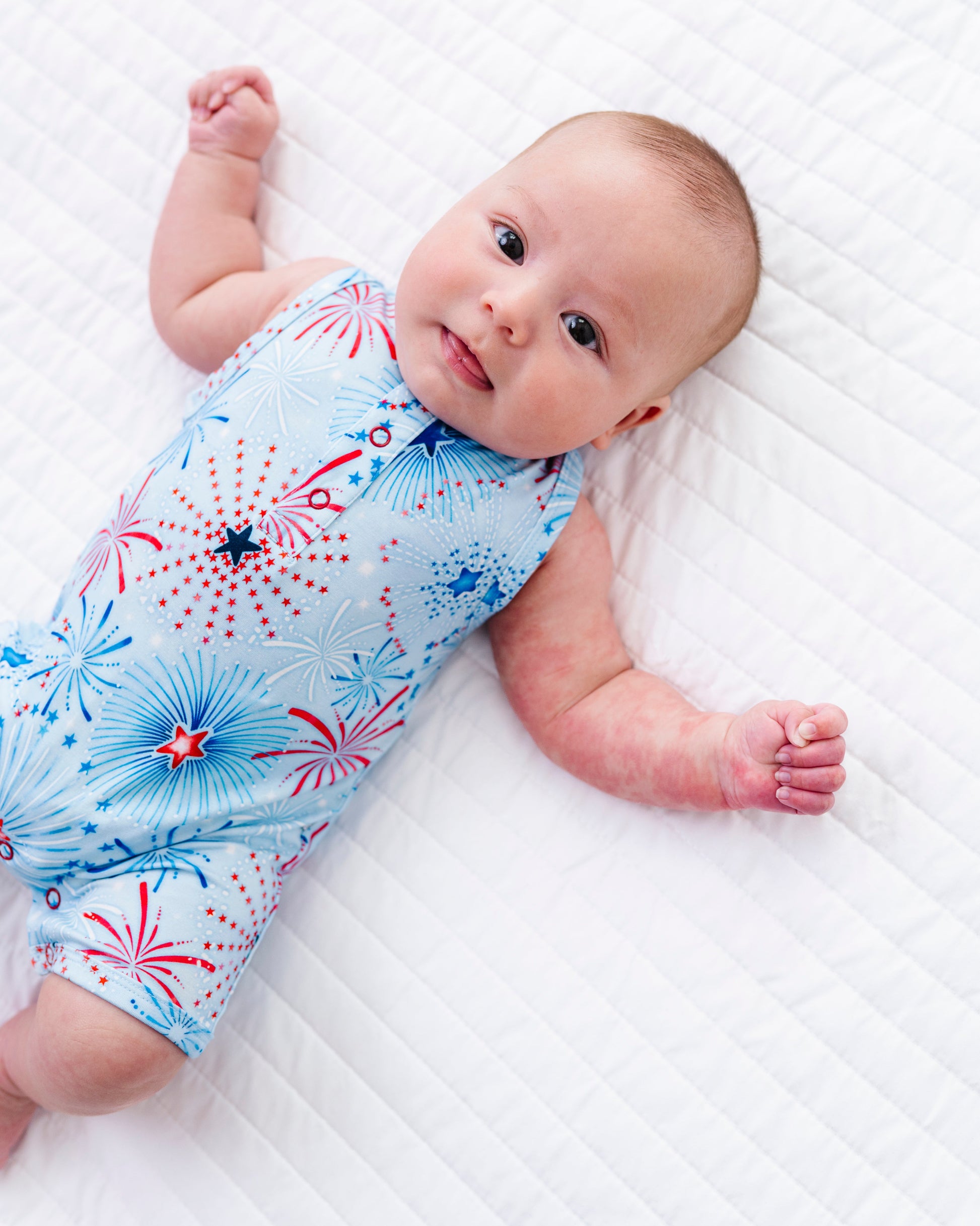 Baby lying on a white surface wearing a red, white, and blue bamboo shortie romper 