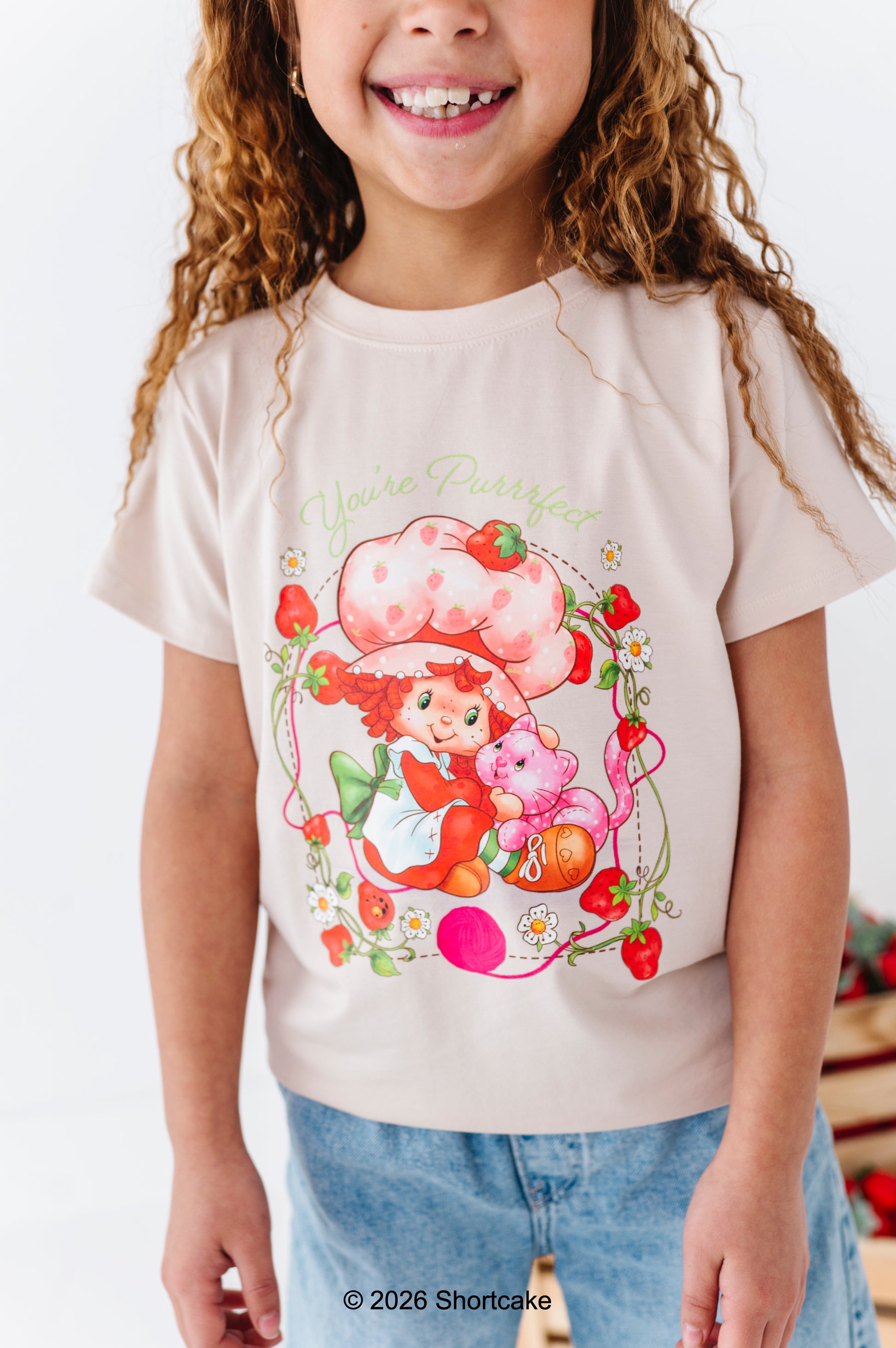 Child wearing a bamboo cotton Strawberry Shortcake™ t-shirt and light wash denim jeans
