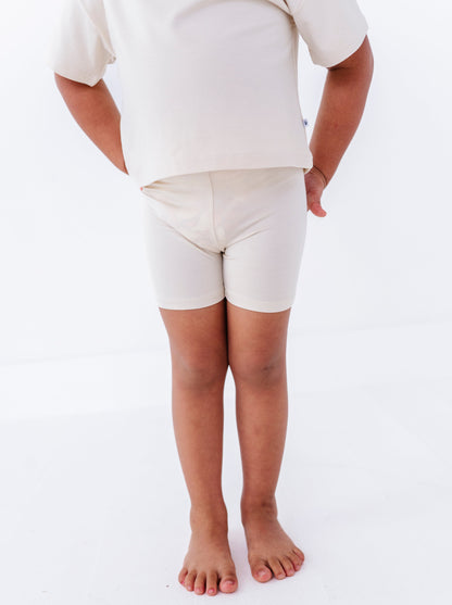 Girl wearing a plain ivory shirt and bamboo biker shorts on a white background