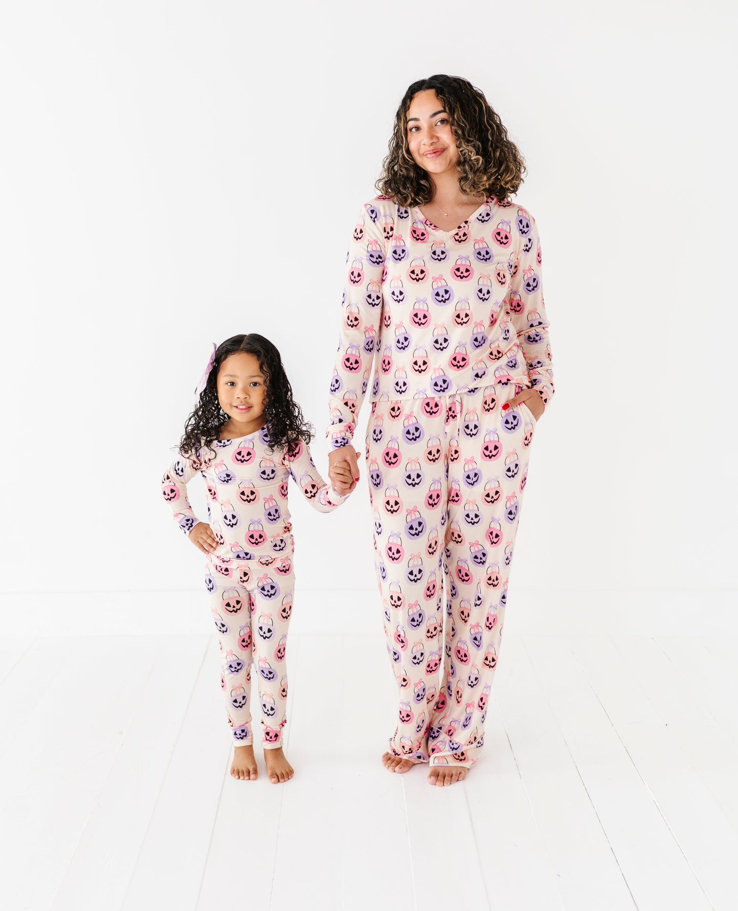 Woman and child wearing matching bamboo pajamas with a Halloween pattern on a white background