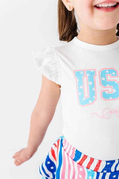Child wearing a white bamboo-cotton t-shirt with 'USA' print and a colorful skort on a white background