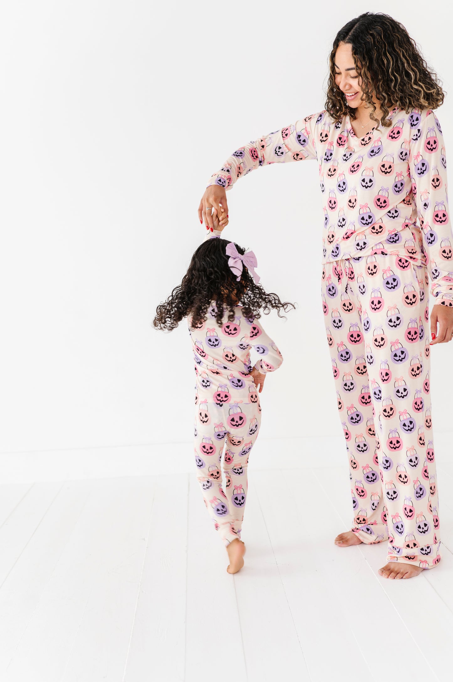 Woman and child wearing matching bamboo pajamas with a Halloween pattern on a white background