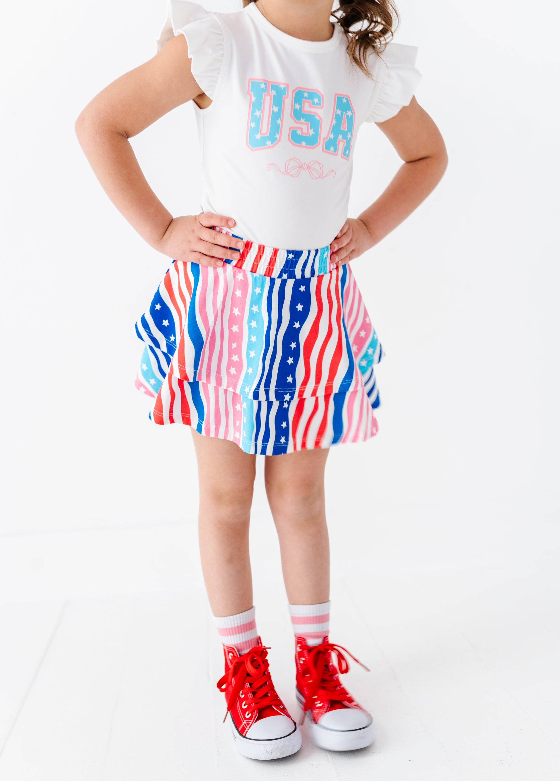 Child wearing a white bamboo top with 'USA' text and a colorful skort on a white background