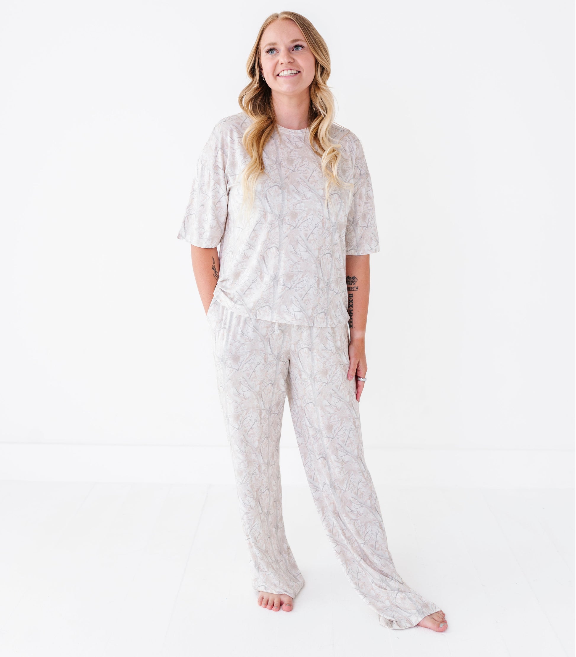 Woman wearing a light gray camo pajama set on a white background