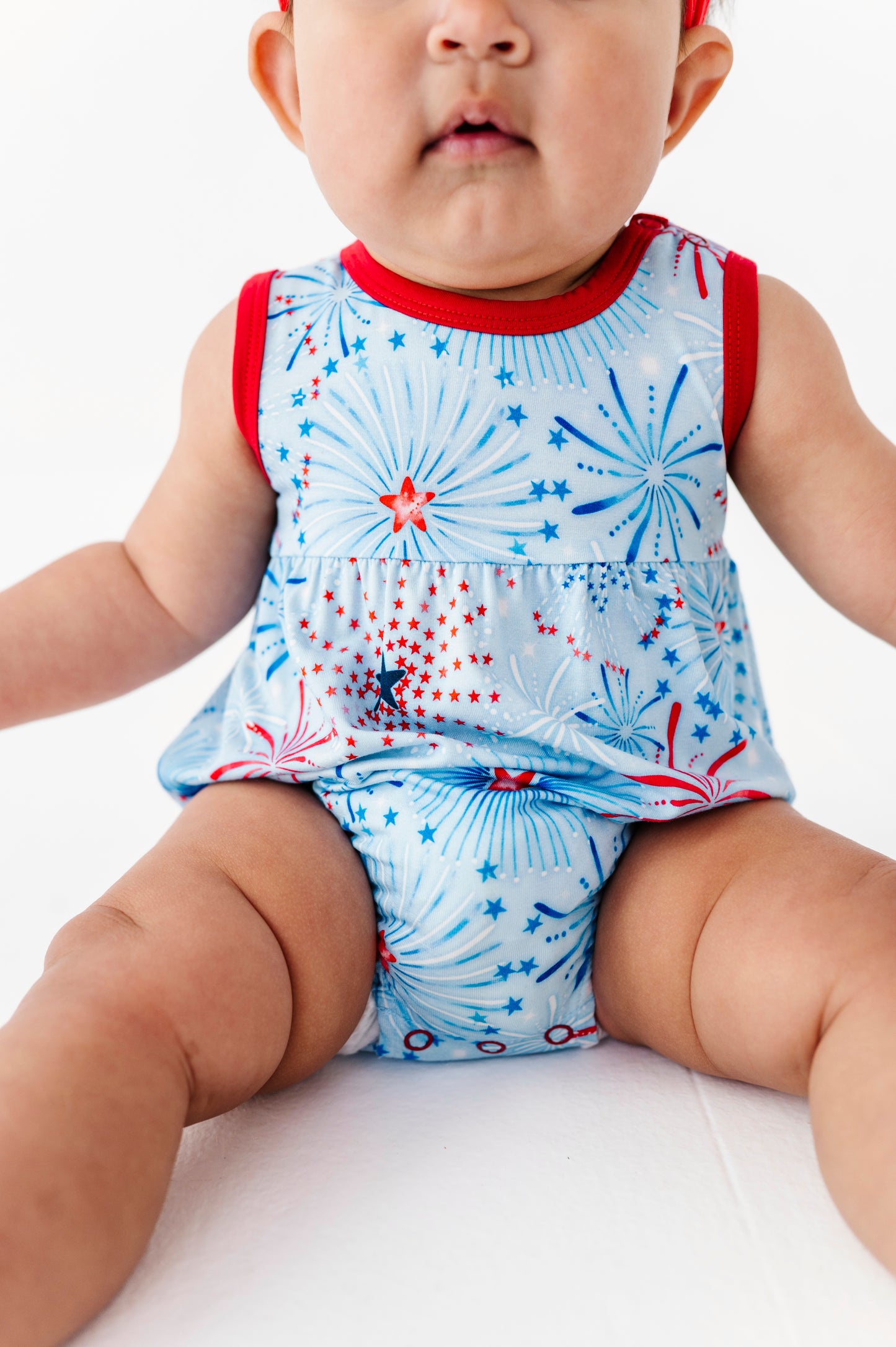 Baby wearing a sleeveless bamboo bubble romper with a firework design on a white background