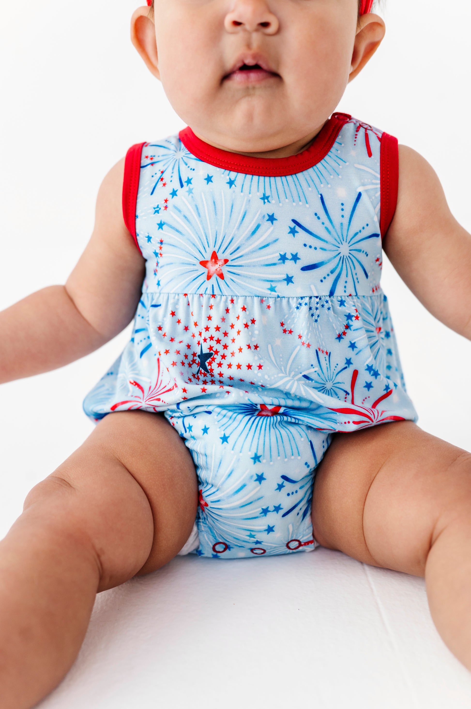Baby wearing a sleeveless bamboo bubble romper with a firework design on a white background