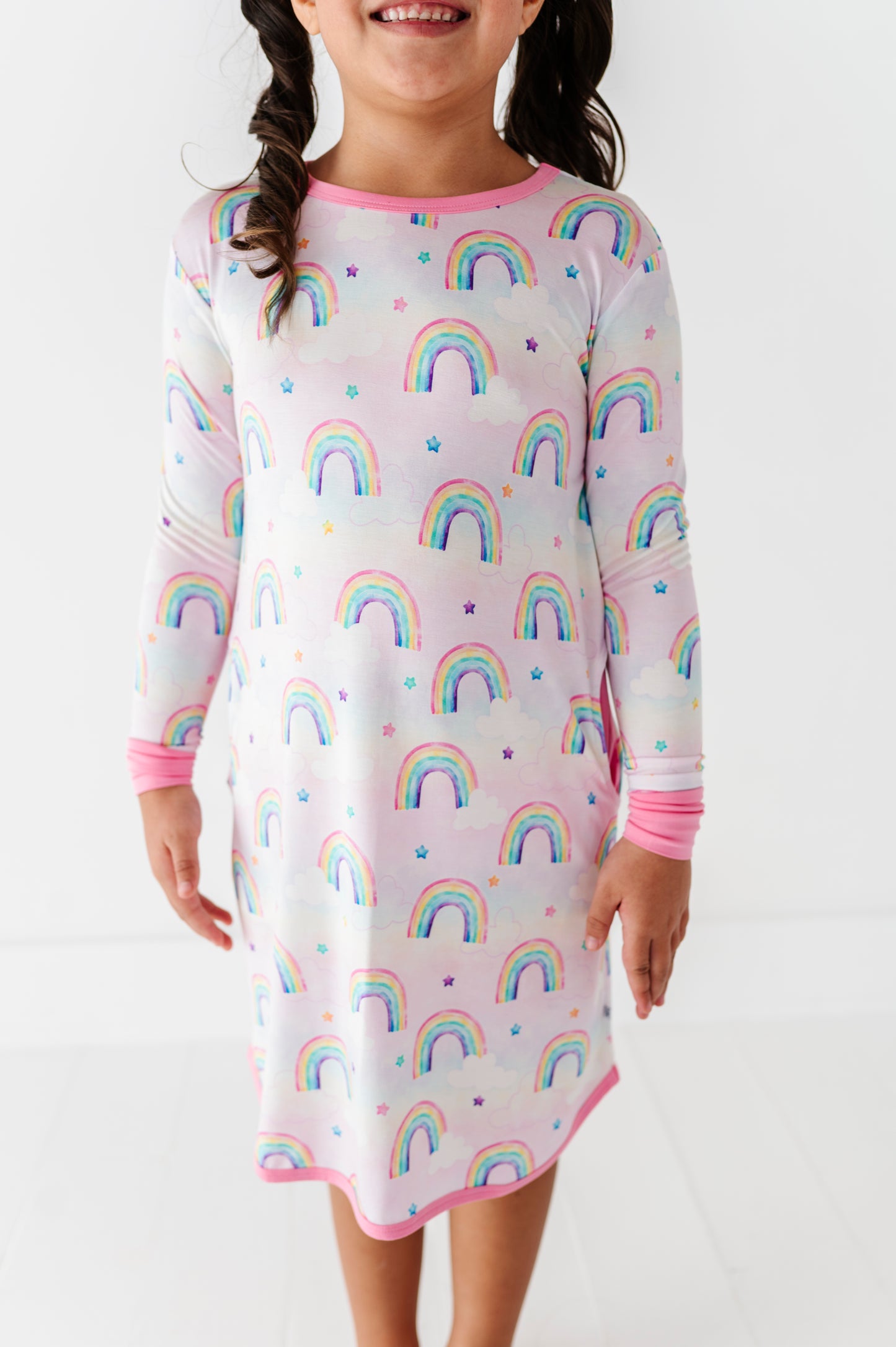 Child wearing a nightgown with watercolor rainbow pattern on a white background