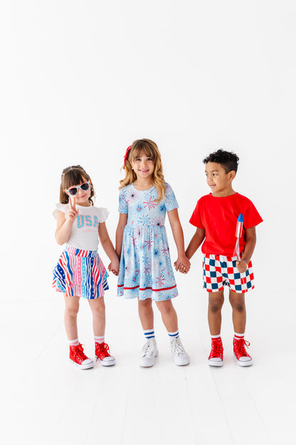 Three children wearing colorful Fourth of July outfits on a white background