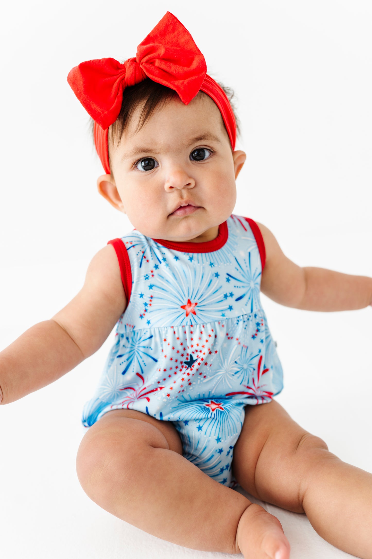 Baby wearing a patriotic bamboo bubble romper with red and white accents and a red headband.