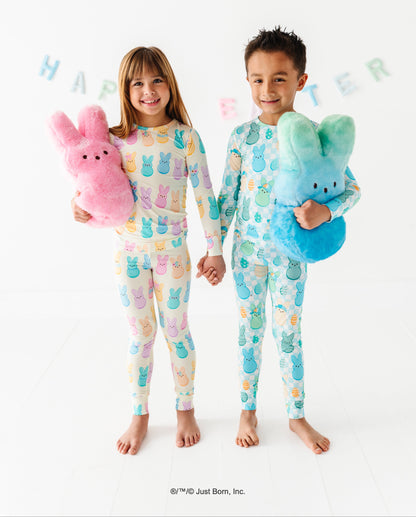 Two children wearing colorful pajamas with PEEPS®  designs, holding stuffed PEEPS®  toys against a white background.