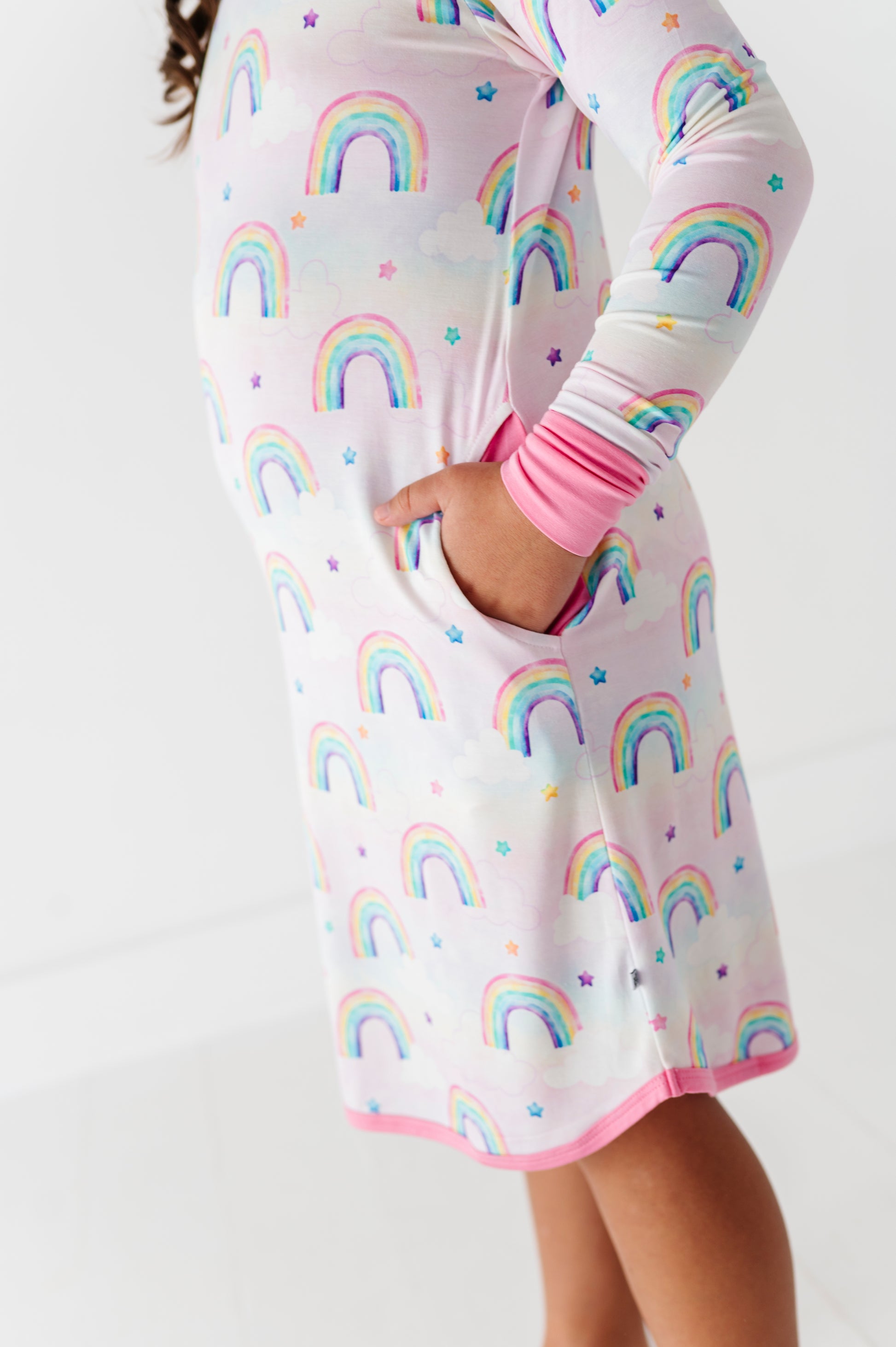 Young girl wearing a watercolor rainbow gown with pink cuffs and trim 